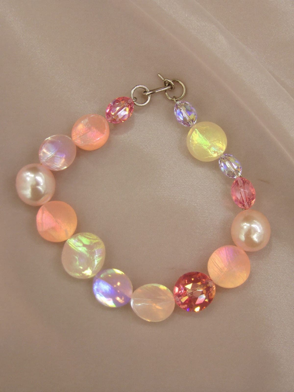 Iridescent pearl choker curved on pale lavender silk with prismatic light