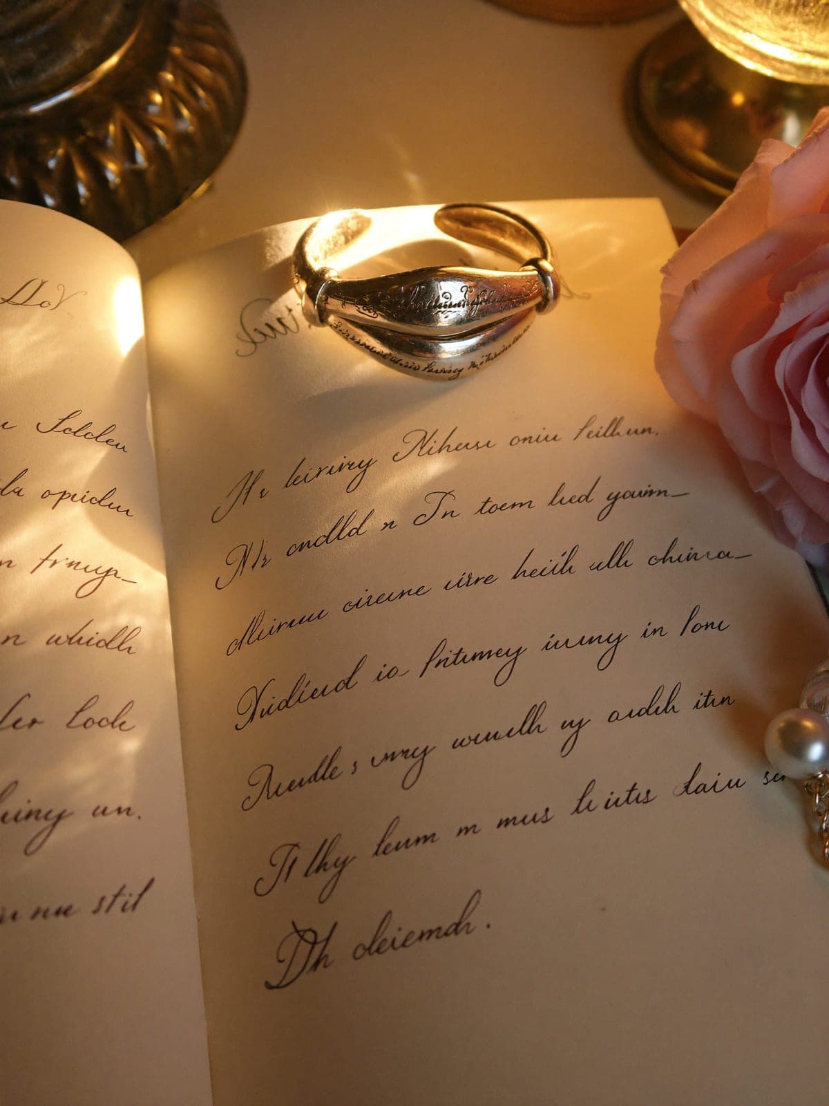 Sculpted champagne gold open cuff with fine engraved script resting on handwritten poetry pages